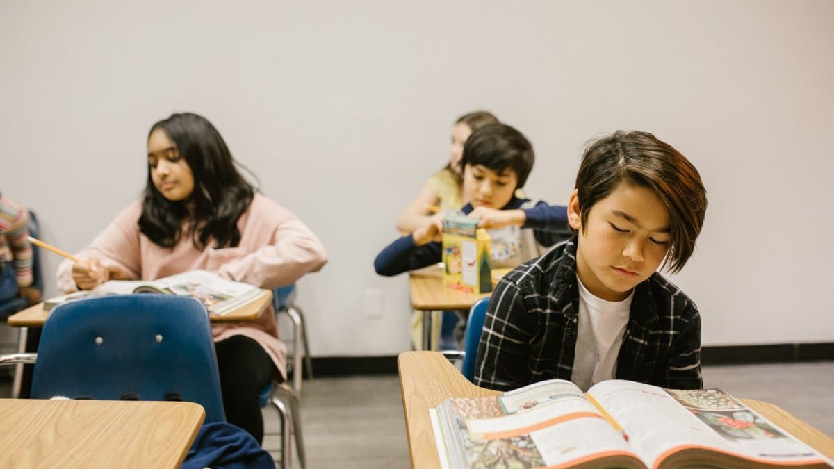 A diverse group of students reading and studying in a classroom setting, focusing on education.