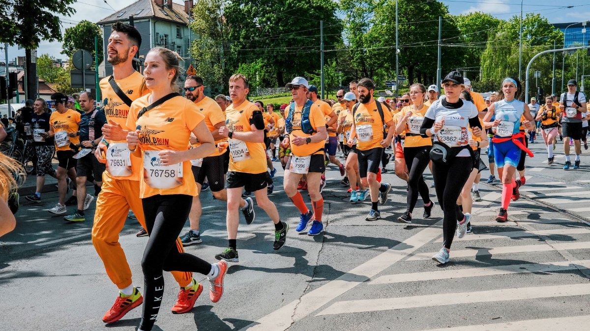 A diverse group of runners competing in a sunny marathon event in Poznań, Poland.