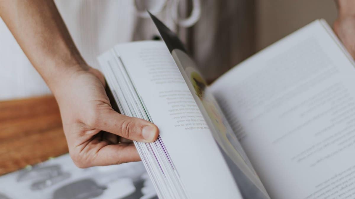 Person flipping through a book, showcasing focus and engagement with reading.