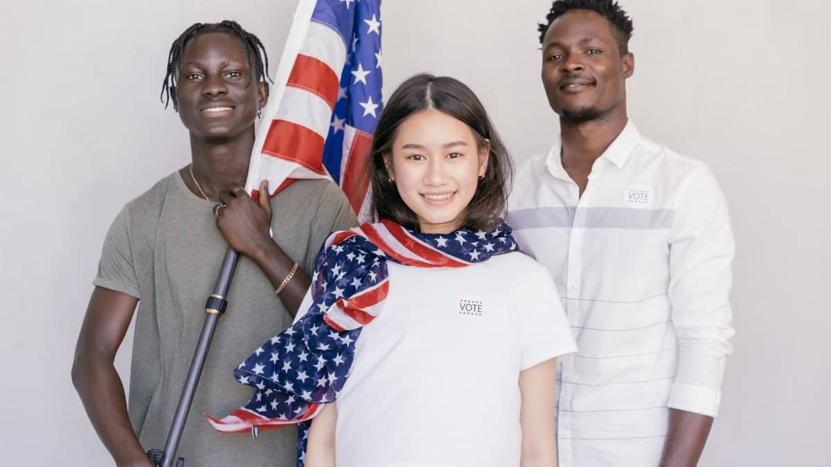 A diverse group of young adults holding an American flag, promoting voting and civic engagement.