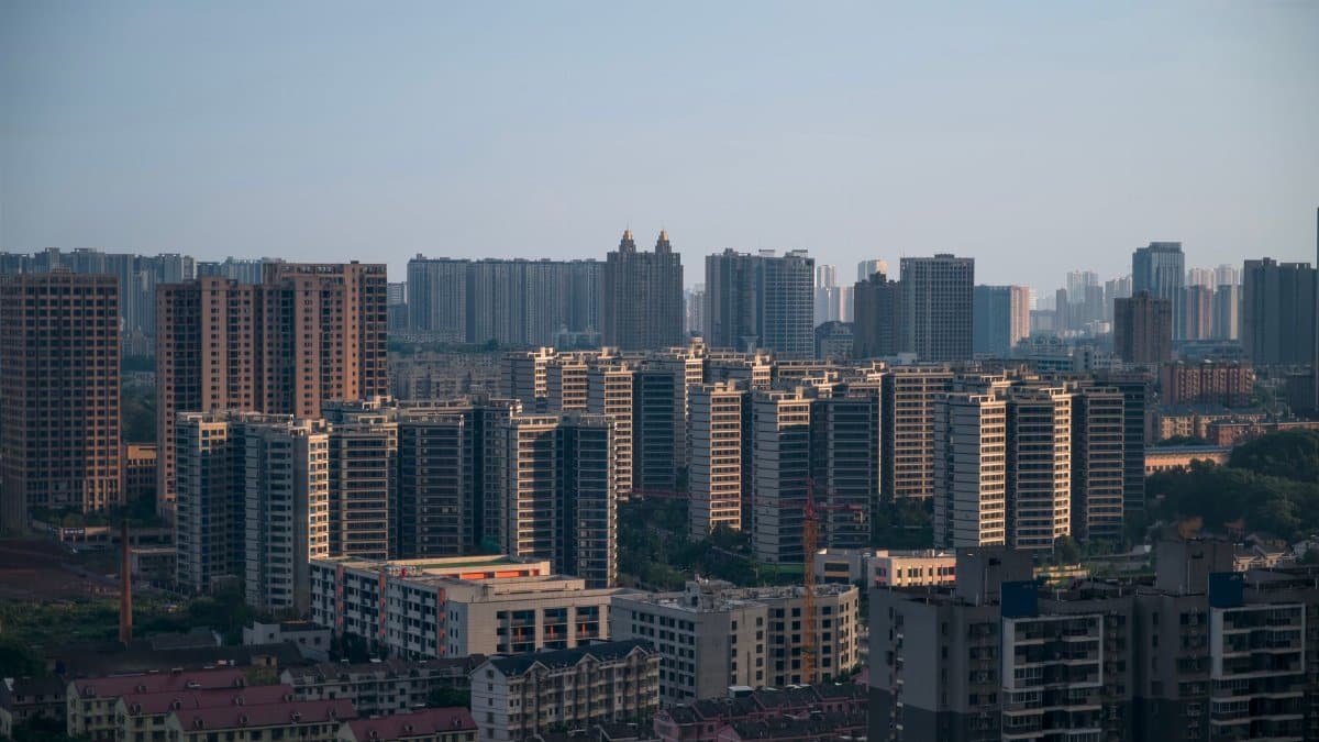Aerial view of a modern city skyline with numerous high-rise apartment buildings under a clear sky.