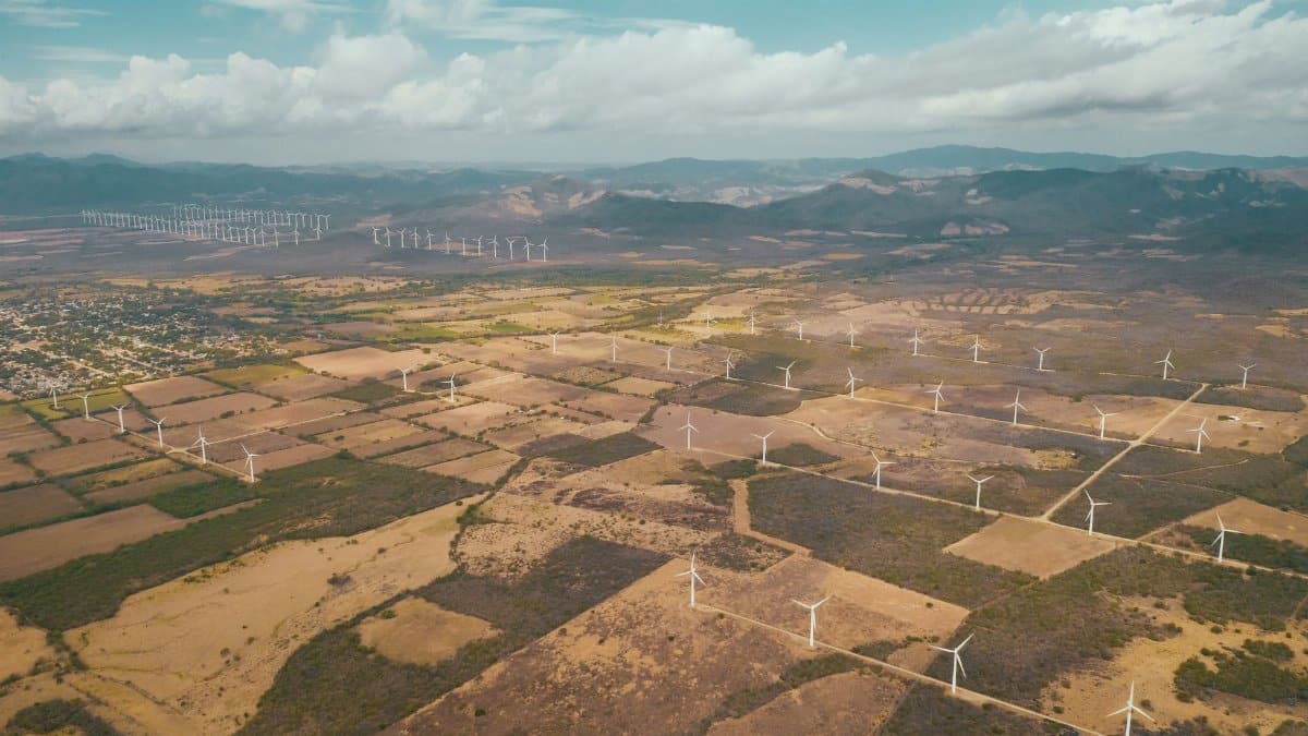 A breathtaking aerial shot of wind turbines on a rural Mexican landscape with mountains.