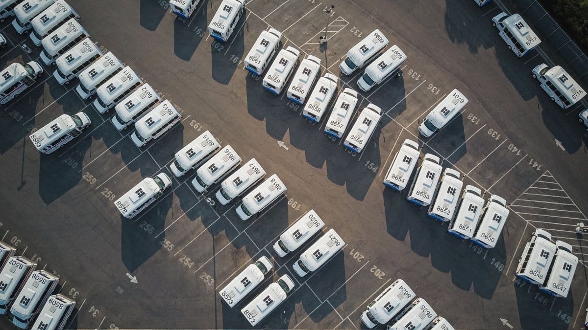Aerial drone shot of neatly organized vans in a large parking lot.