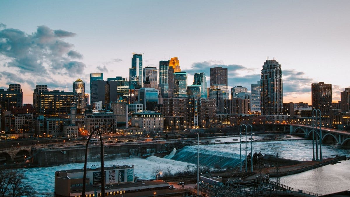 Stunning view of Minneapolis skyline with river and bridge at sunset.