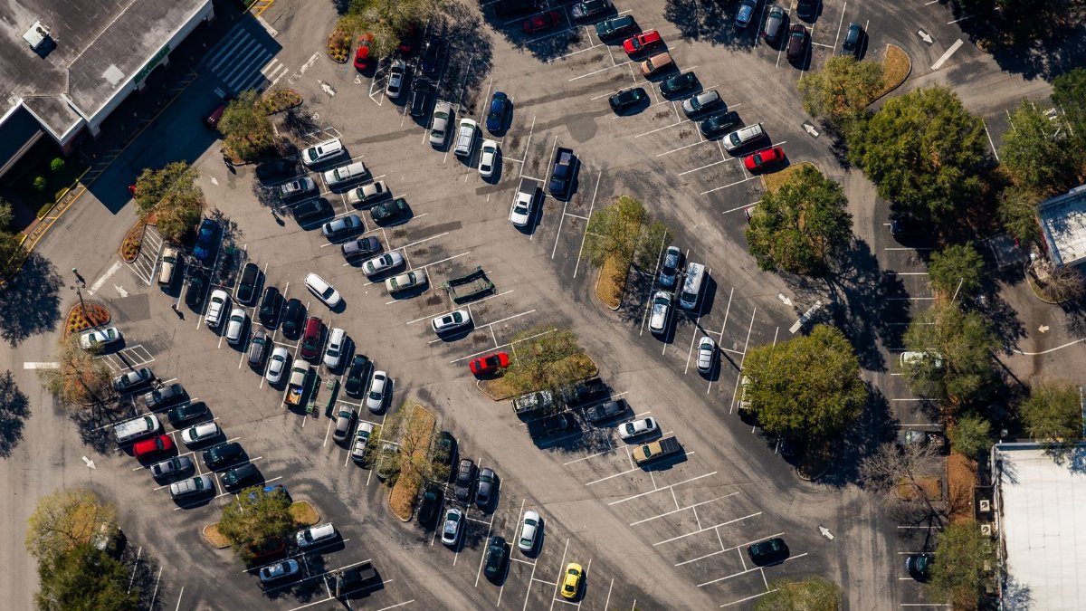 Aerial view of a busy parking lot in Florida with parked cars and surrounding trees.