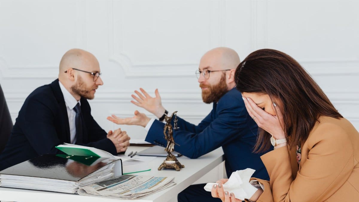 A lawyer mediates an emotional settlement discussion with a distressed couple in a legal office.
