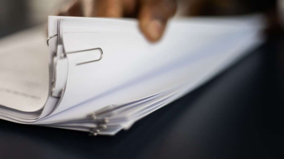 Detailed image of paper stacks held together by paperclips, showcasing organizational tools.