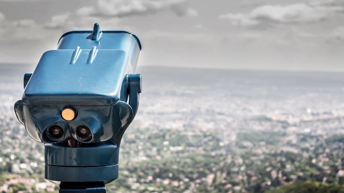 A coin-operated viewer overlooking a vast cityscape under a cloudy sky.
