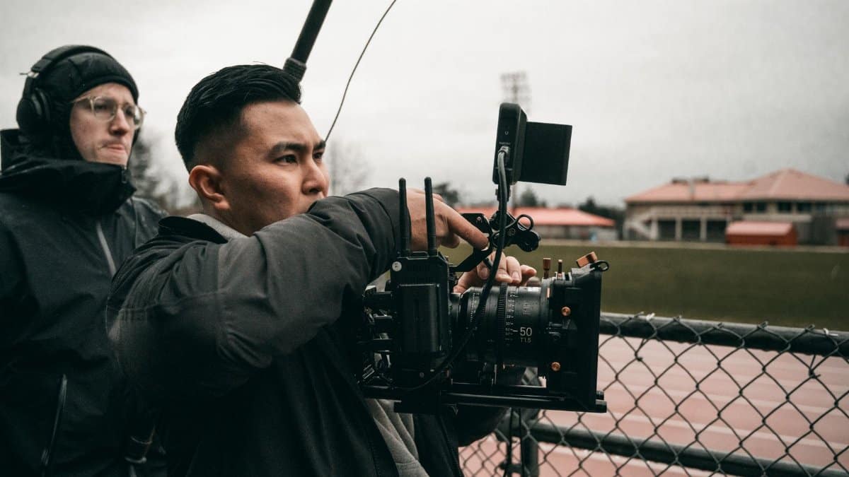 A dedicated cameraman capturing video at an outdoor sports field.