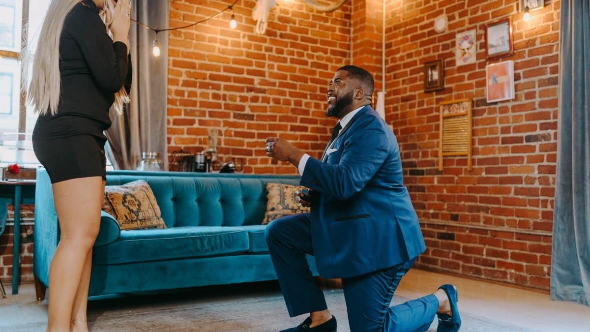 A man proposes to a woman indoors, capturing a romantic and intimate moment.