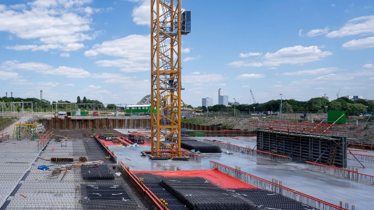 A vibrant construction site with a prominent yellow tower crane under a bright blue sky.