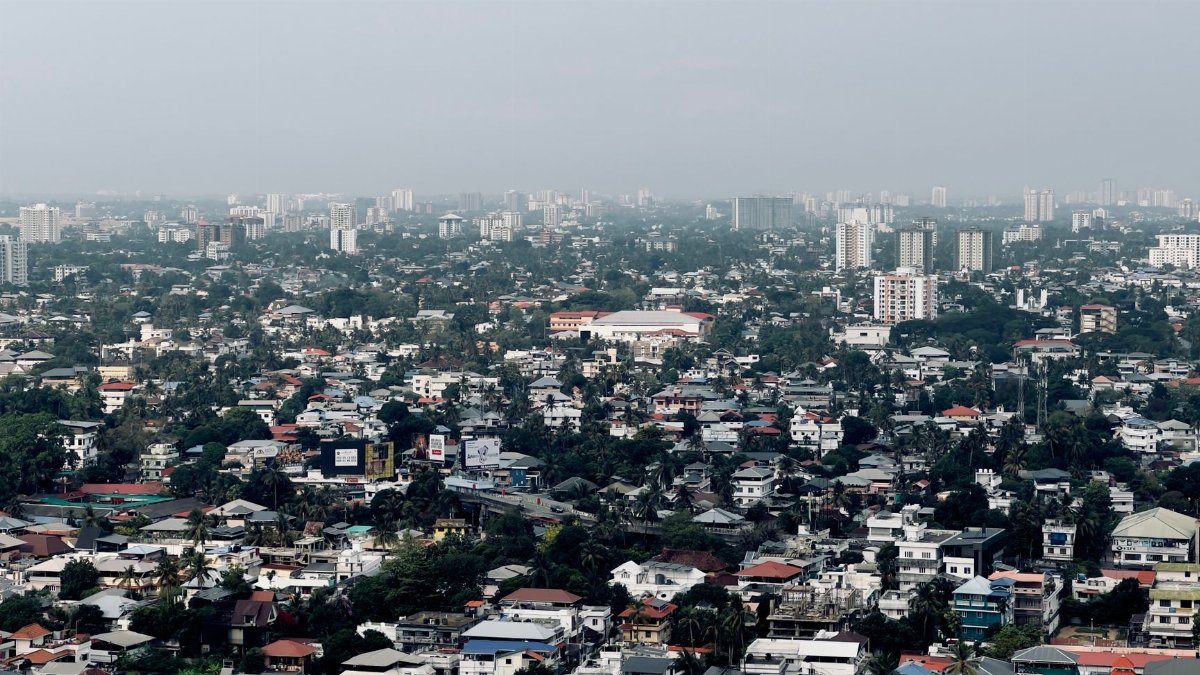 Distance aerial view capturing a sprawling urban cityscape with various buildings and greenery.