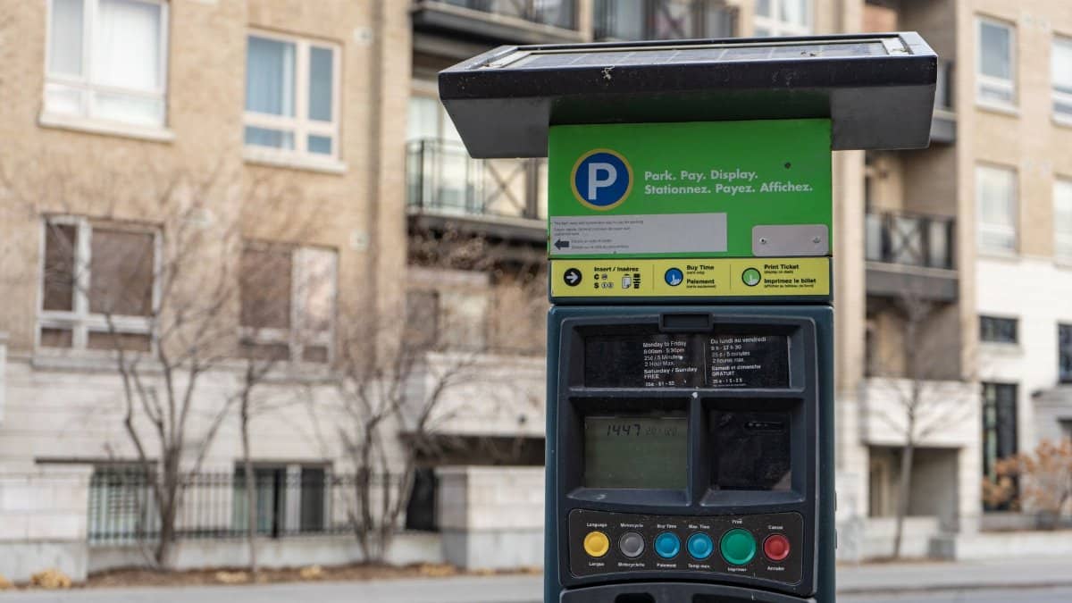Close-up of a parking meter on an urban street with residential buildings in Ottawa, Canada.