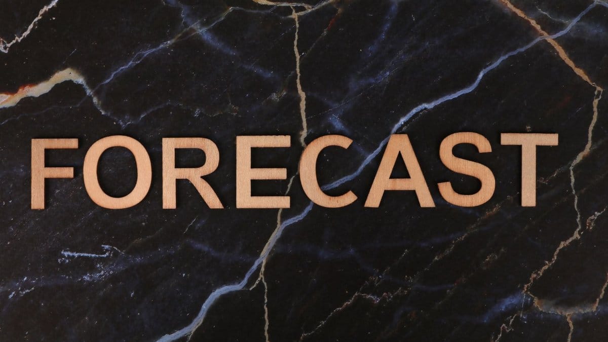 The word 'FORECAST' in wooden letters on a dark marble background.