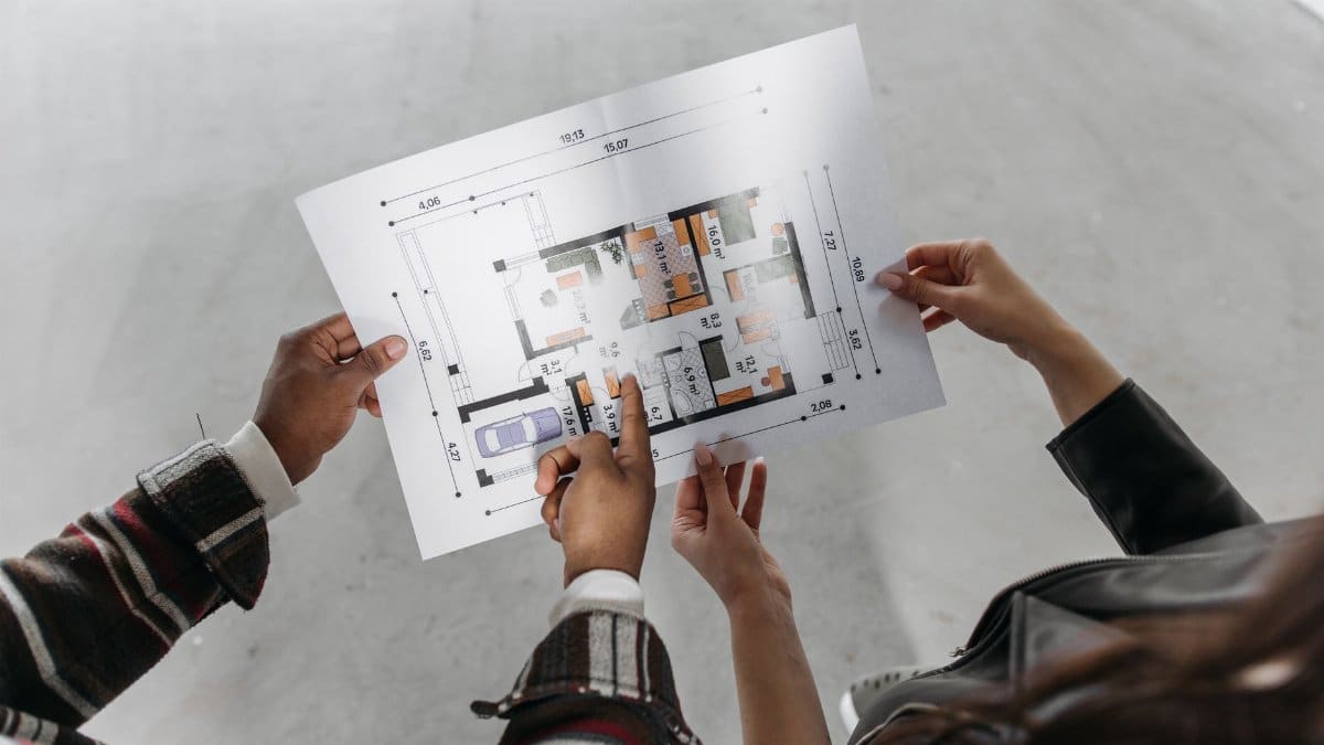 Two people reviewing architectural plans and measuring a new home design.