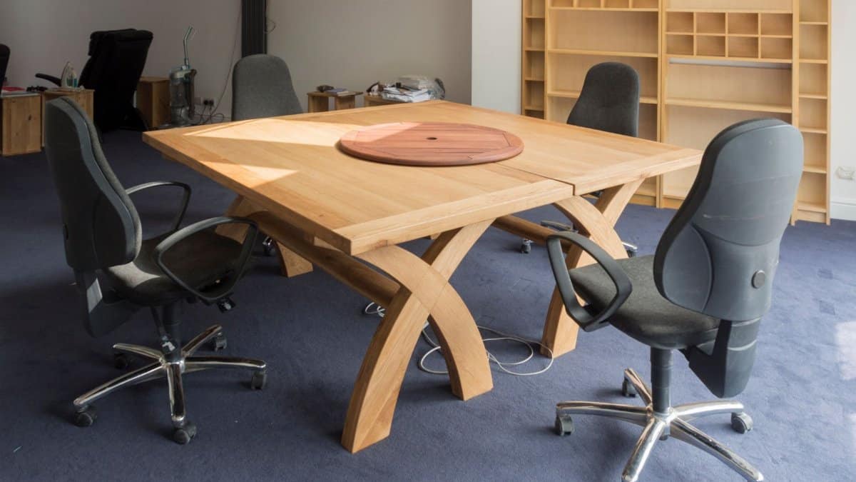 Contemporary office meeting room featuring a unique wooden table design and ergonomic chairs.