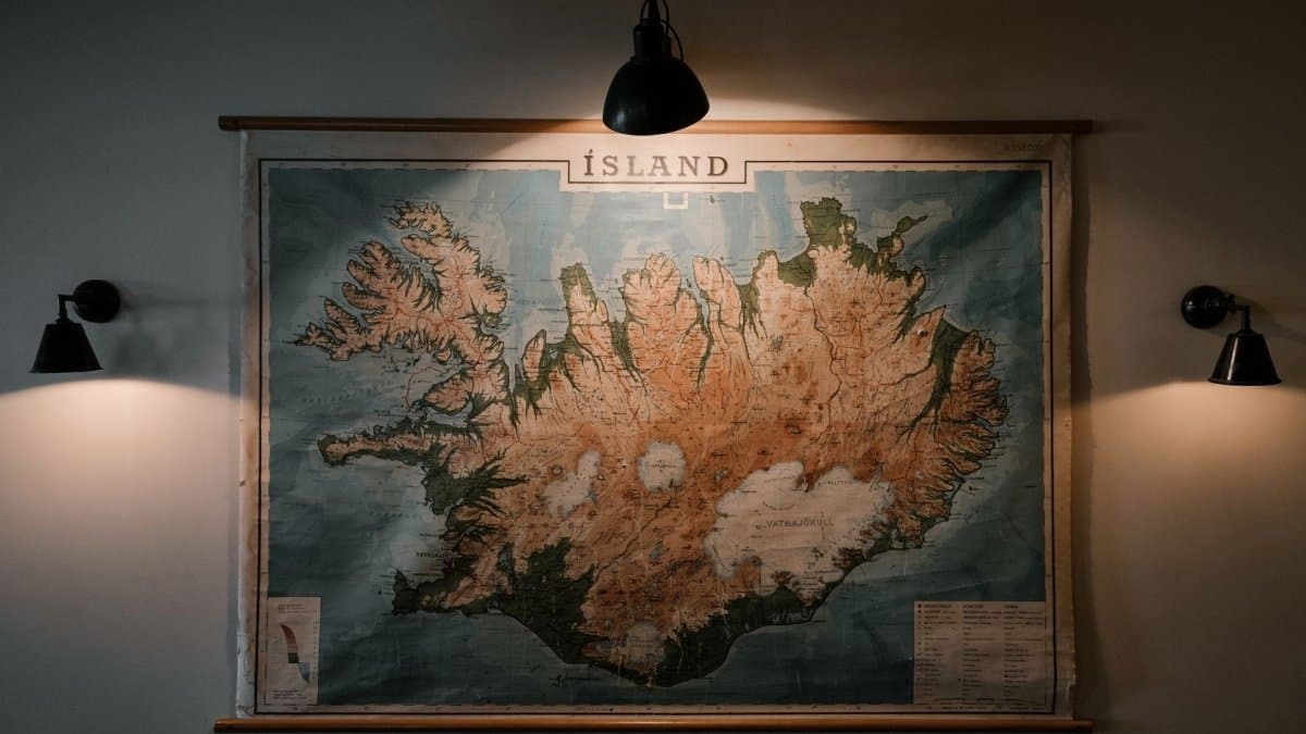 Shabby looking paper map of Iceland hung on wall and lit up with small lamps in darkened room of research station