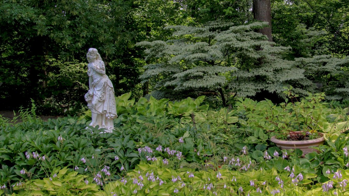 A beautiful garden statue adorned with lush foliage and flowers, creating a serene nature scene.