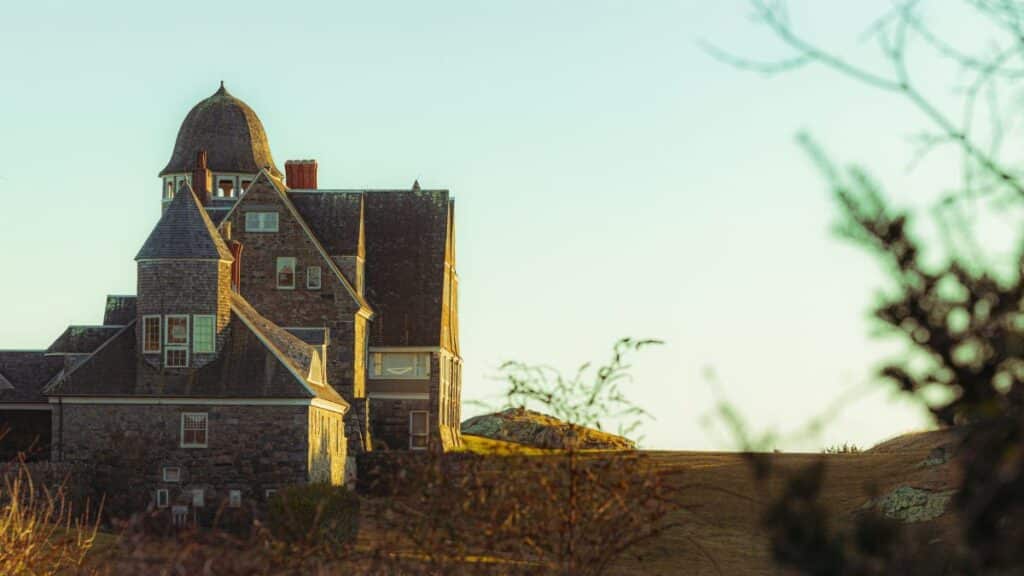 A picturesque stone house in New England, highlighting coastal architecture under a warm sunset.