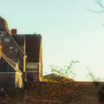 A picturesque stone house in New England, highlighting coastal architecture under a warm sunset.