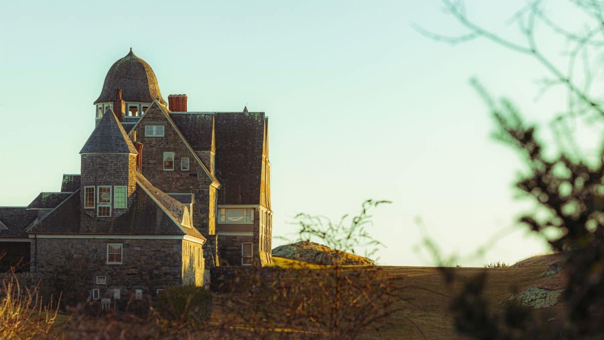 A picturesque stone house in New England, highlighting coastal architecture under a warm sunset.