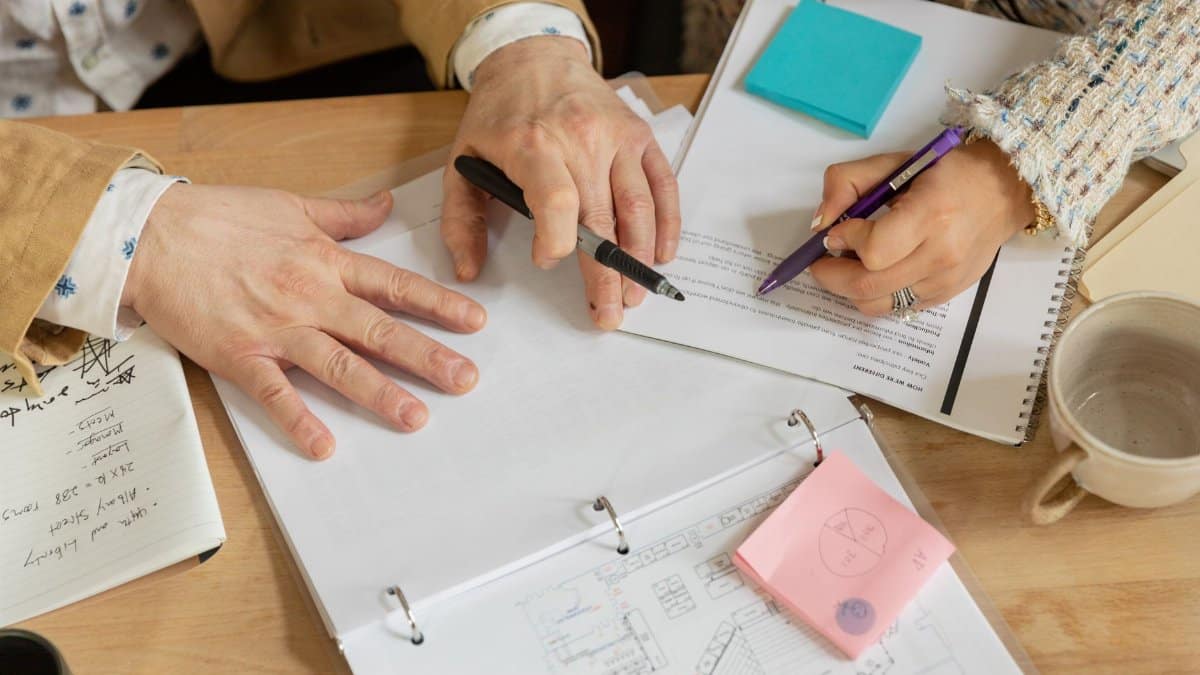 Close-up of two coworkers collaborating over documents and planning in an office setting.