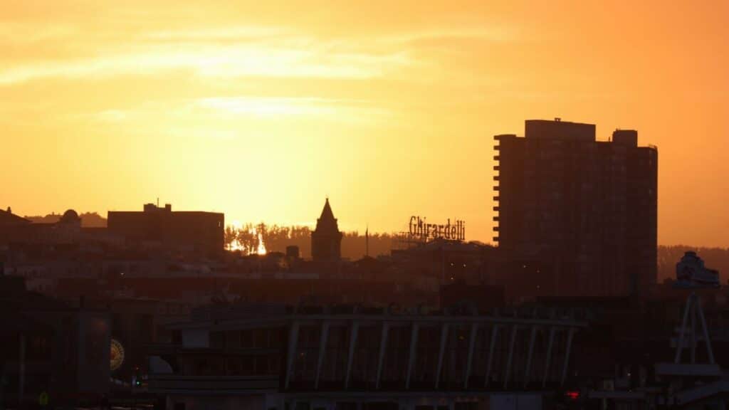Silhouette of San Francisco cityscape with Ghirardelli sign at sunset.