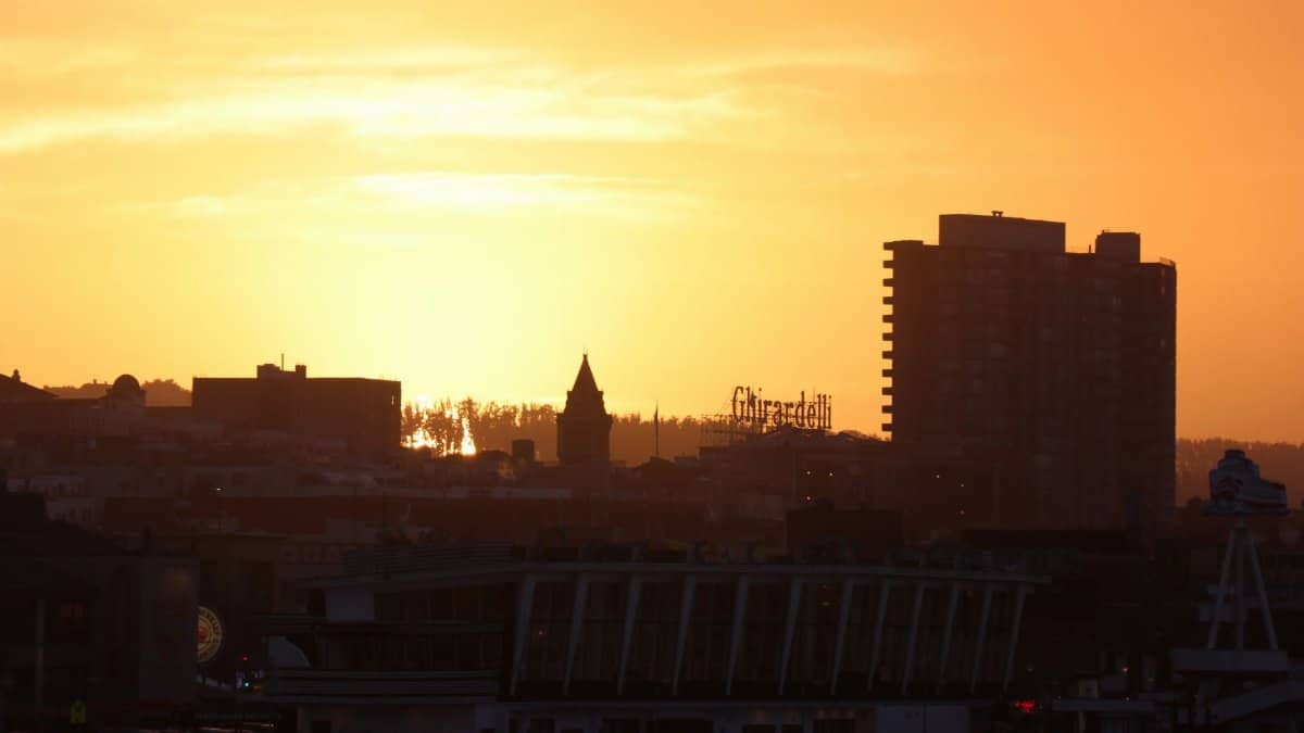 Silhouette of San Francisco cityscape with Ghirardelli sign at sunset.