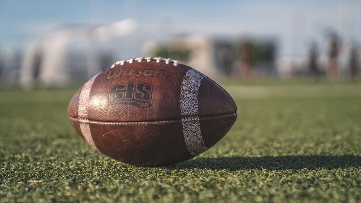 Close-up of a Wilson football on green grass in an outdoor sports setting, perfect for sports-themed visuals.