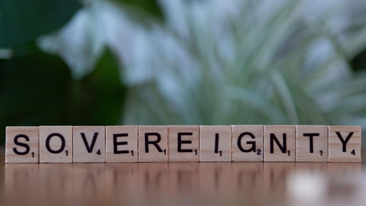 Wooden Scrabble tiles spelling out 'Sovereignty' on a blurred natural background.
