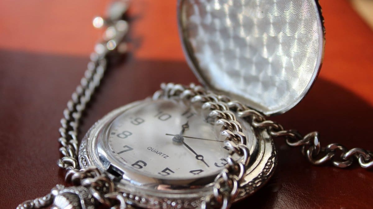 Close-up of a vintage silver pocket watch with chain, elegantly designed.