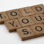 Close-up of wooden Scrabble tiles spelling 'Told You So' on a white background.