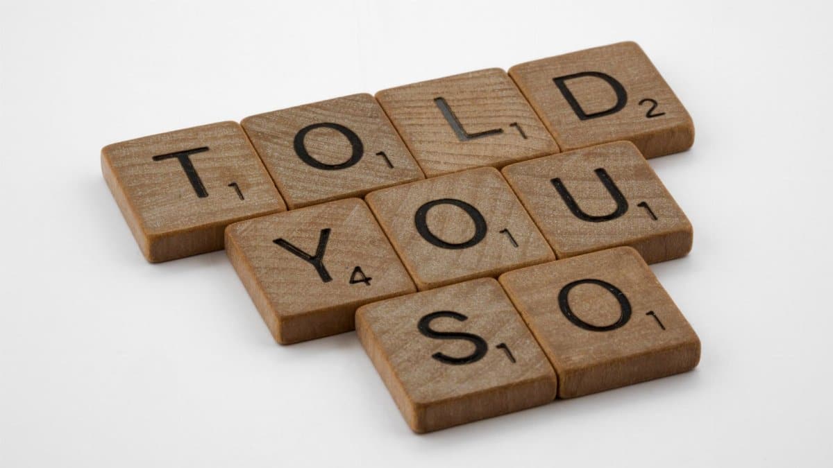 Close-up of wooden Scrabble tiles spelling 'Told You So' on a white background.