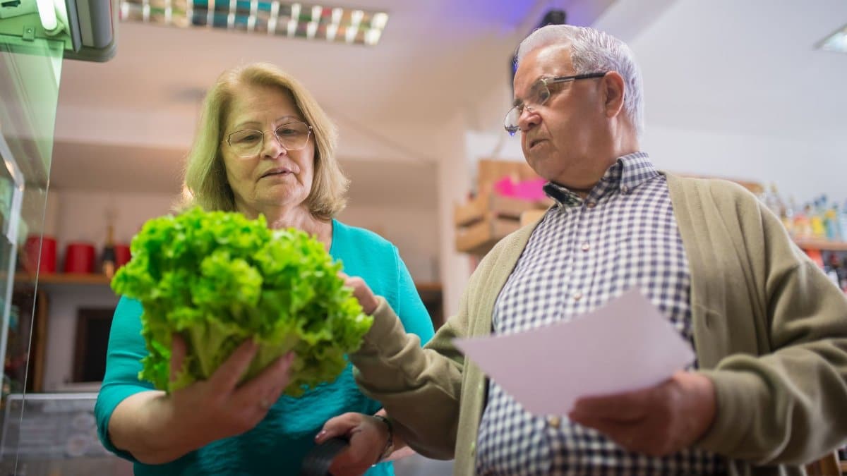 Elderly couple picking fresh lettuce together in a grocery store in Portugal.