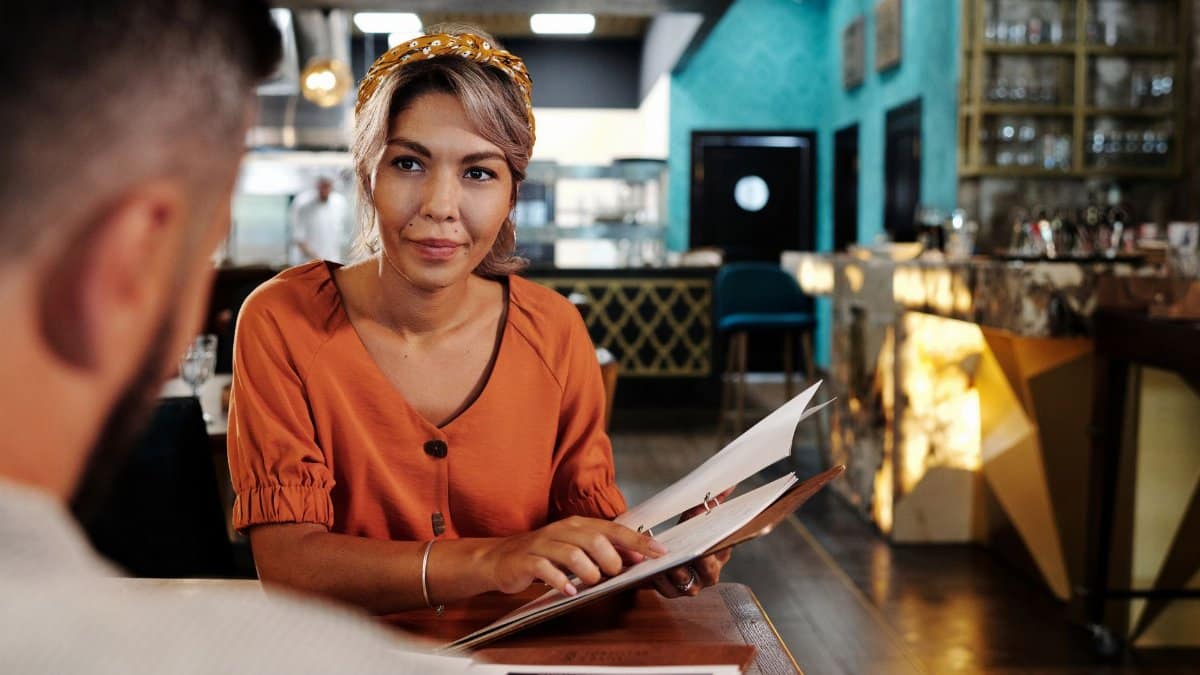 A couple enjoying a relaxed conversation while choosing from the menu in a modern café setting.