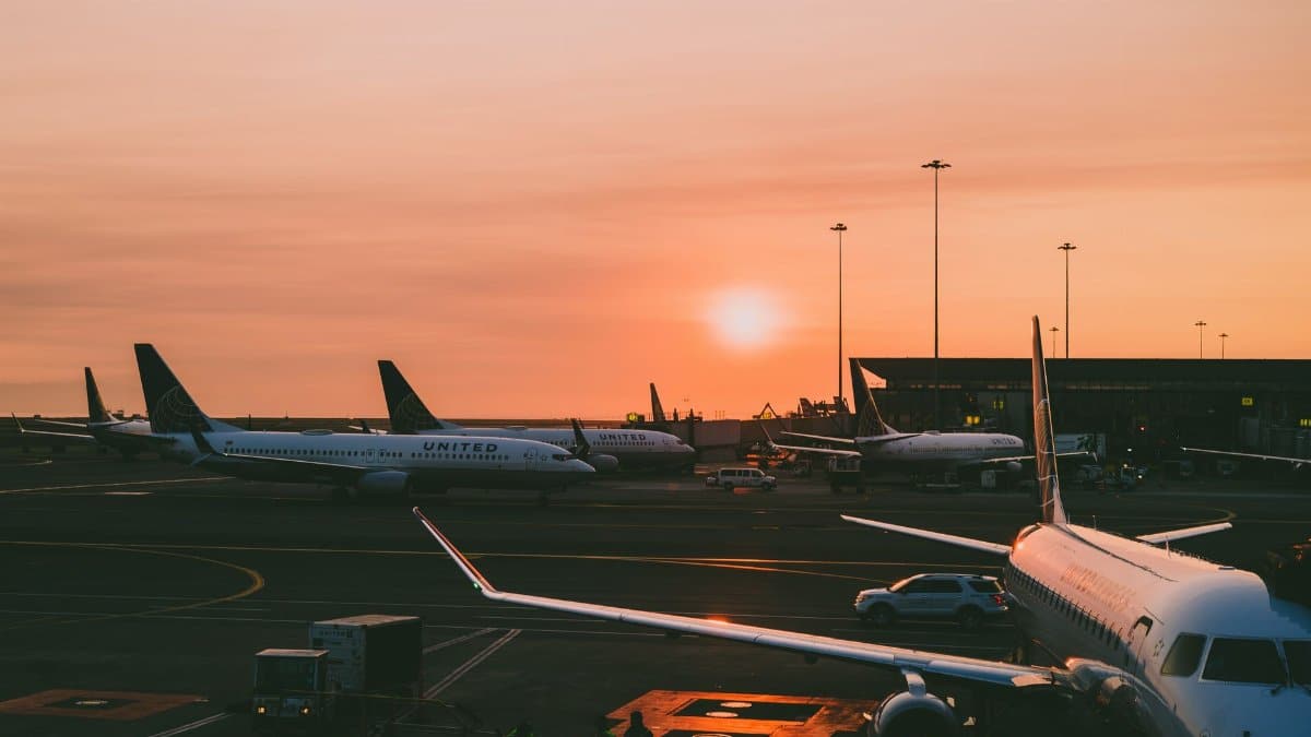 A serene view of parked airplanes at an airport with a beautiful sunset in the background.