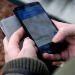 Close-up of hands using a map app on a smartphone outdoors, showcasing GPS navigation.