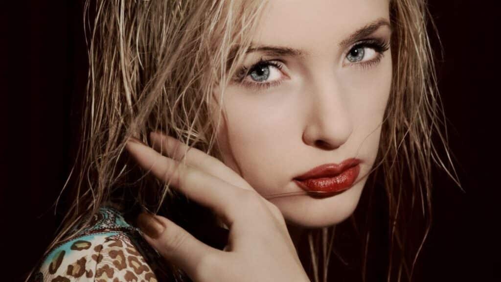 Close-up portrait of an elegant woman with striking gray eyes and wet hair.