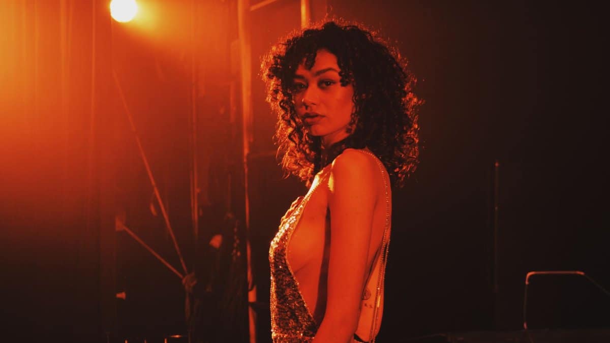 A woman in a glamorous dress poses under dramatic spotlight, captured with a Canon EOS 400D.