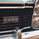 Close-up view of a vintage Ford car's grille and headlight, emphasizing its classic design.