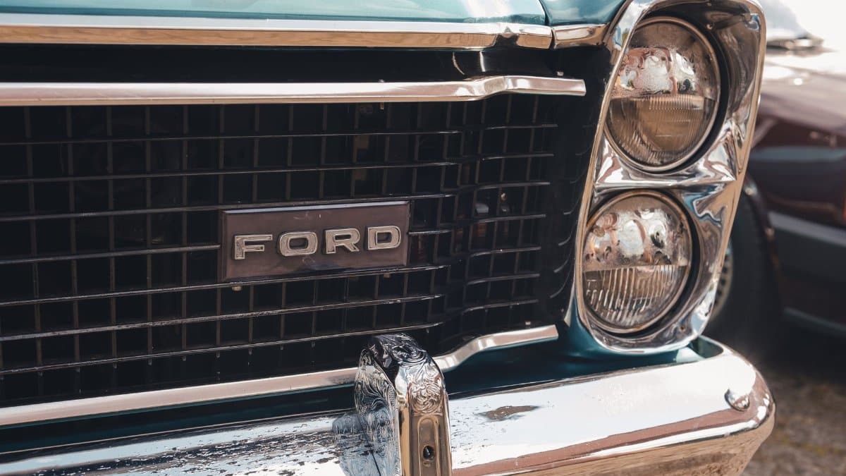 Close-up view of a vintage Ford car's grille and headlight, emphasizing its classic design.