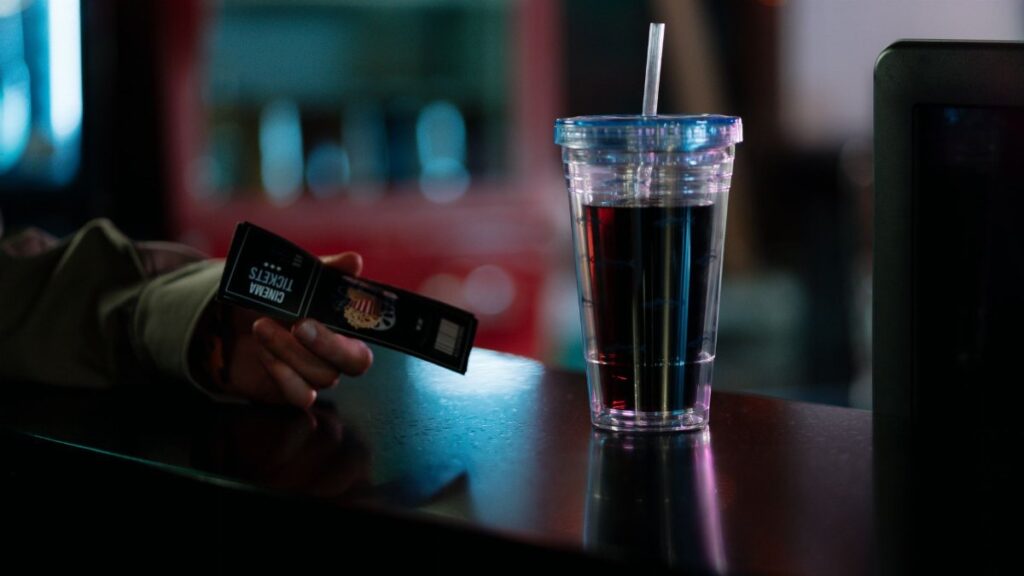 Close-up of cinema tickets and a soda cup on a counter. Ideal for entertainment themes.