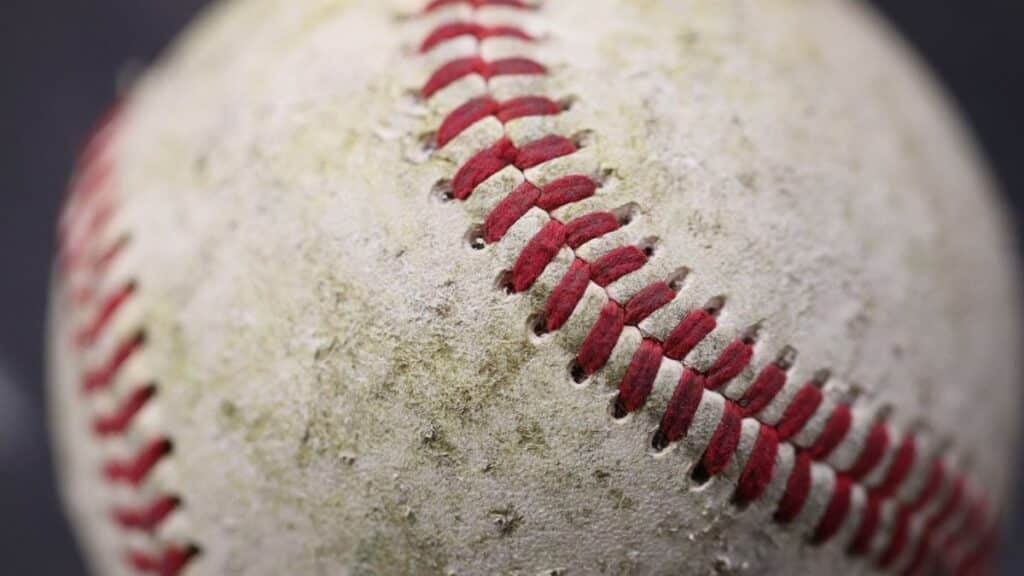 Detailed close-up of a worn baseball showcasing red stitching on its surface.