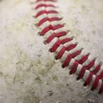 Detailed close-up of a worn baseball showcasing red stitching on its surface.