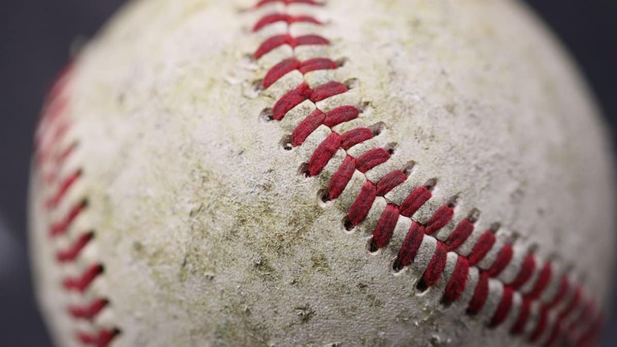 Detailed close-up of a worn baseball showcasing red stitching on its surface.