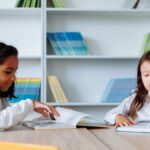 Two young girls enjoying books in a vibrant school library setting.