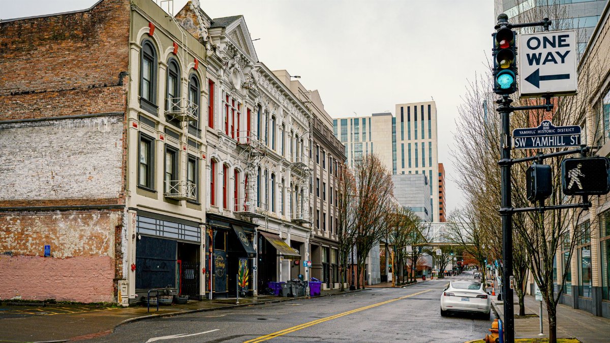 A rainy street view of Portland's Yamhill Historic District with historic and modern buildings.