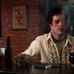 A person with bold makeup enjoys beverages at a dimly lit vintage bar, exuding style and nostalgia.