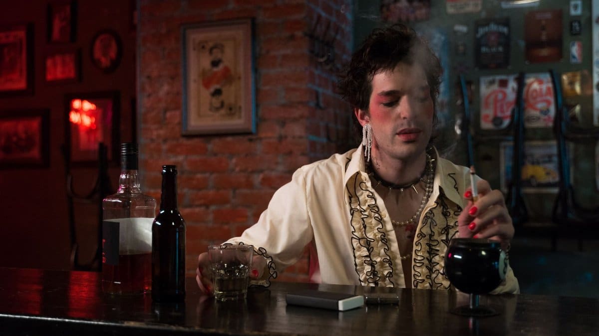 A person with bold makeup enjoys beverages at a dimly lit vintage bar, exuding style and nostalgia.