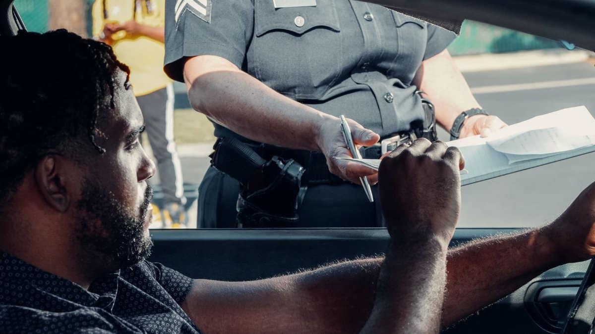 Police officer handing a traffic ticket to a driver during roadside inspection.